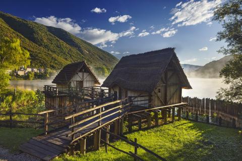 Two pile dwelling constructed as in prehistory framed by the natura environment of the lake shore