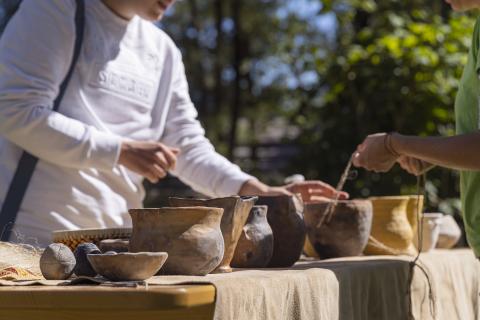 A visitor is touching some replicas of vessels dated between Neolithic and Bronze Age