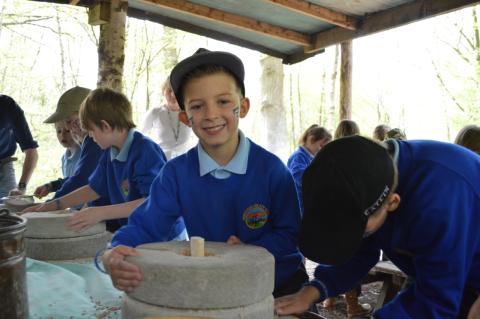 Boy grinding Grains on a quern stone